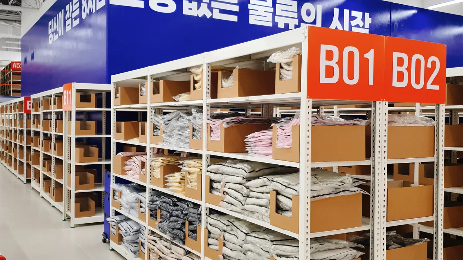 DCF 센터 B존 경량랙. 랙마다 B01·B02 구역 번호가 붙어 있고 의류가 칸별로 보관돼 있다.